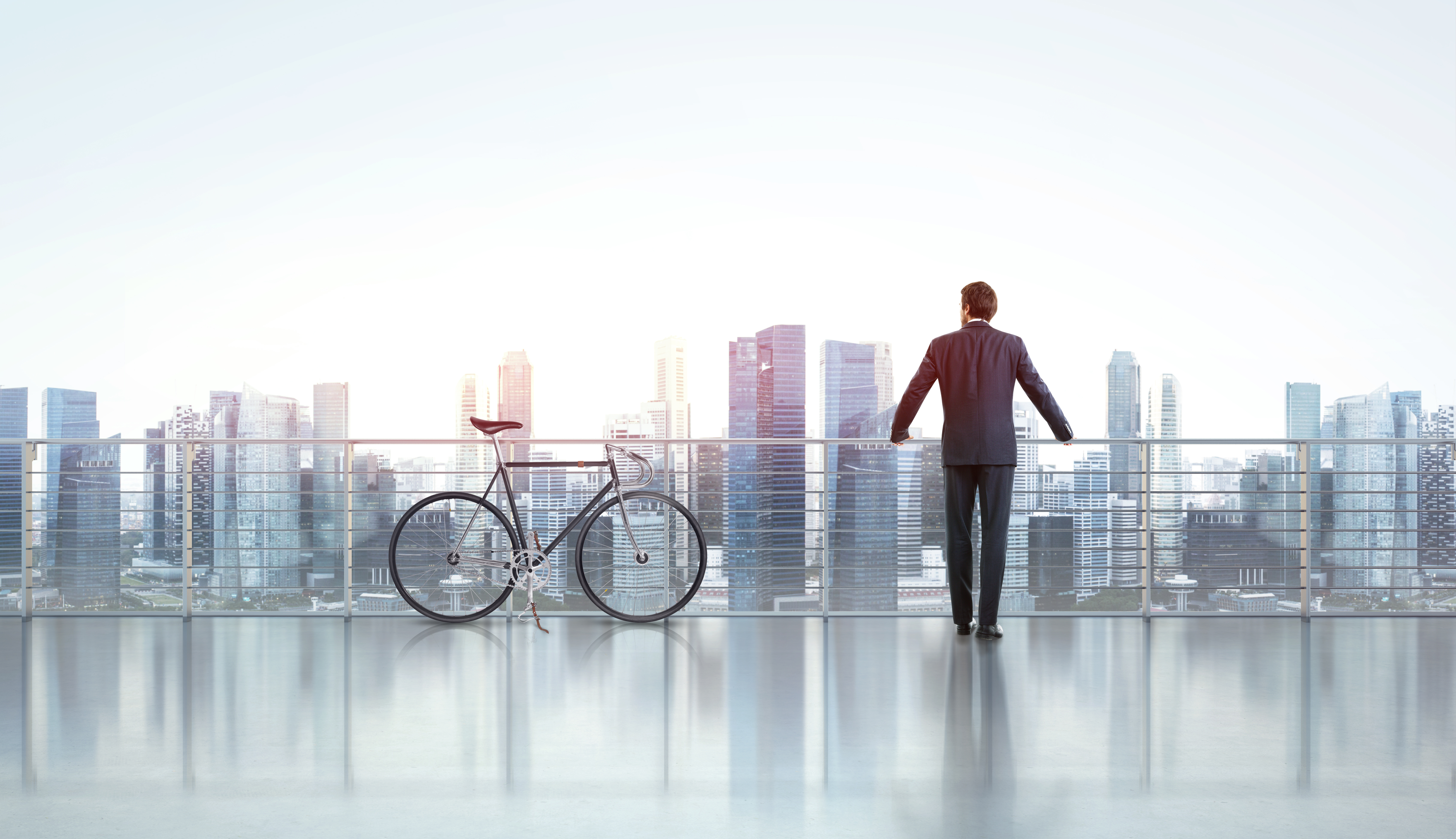 Businessman with bicycle looks at city